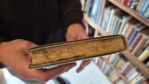 An old hardcover book being opened carefully to avoid cracking the spine