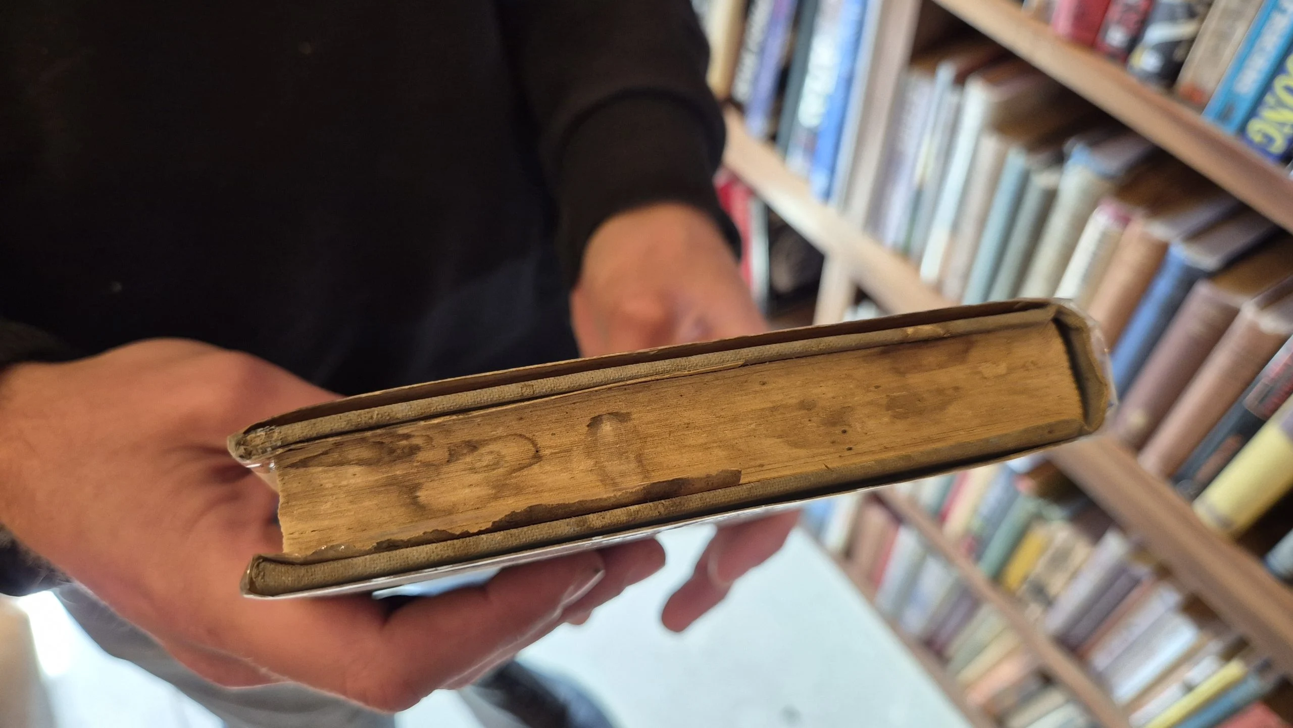 An old hardcover book being opened carefully to avoid cracking the spine