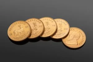 Five gold Krugerrand coins, one showing Paul Kruger and the rest the springbok, at Midlands Books